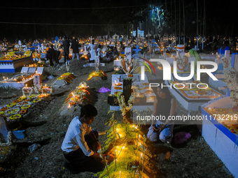 A family lights candles over their relative's grave during All Souls' Day observance at a cemetery 80 kilometers outside Kolkata, India, on...