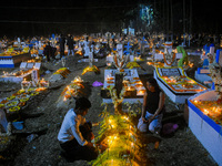 A family lights candles over their relative's grave during All Souls' Day observance at a cemetery 80 kilometers outside Kolkata, India, on...