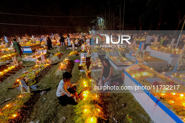 A family lights candles over their relative's grave during All Souls' Day observance at a cemetery 80 kilometers outside Kolkata, India, on...