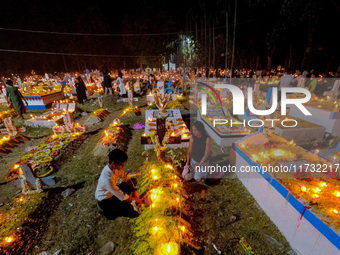 A family lights candles over their relative's grave during All Souls' Day observance at a cemetery 80 kilometers outside Kolkata, India, on...