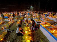 A family lights candles over their relative's grave during All Souls' Day observance at a cemetery 80 kilometers outside Kolkata, India, on...