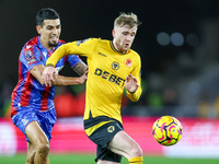 Number 20, Tommy Doyle of Wolves, is pressed by number 12, Daniel Munoz of Crystal Palace during the Premier League match between Wolverhamp...