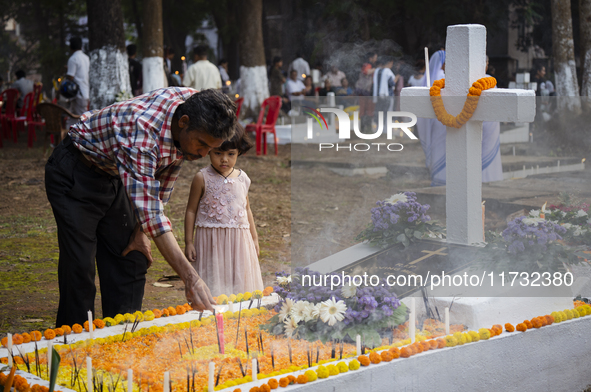 People from the Christian community light candles and offer prayers on the grave of their relative during the All Souls' Day observation in...