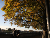 People walk among trees with autumn yellow leaves in Krakow, Poland, on October 19, 2024. (