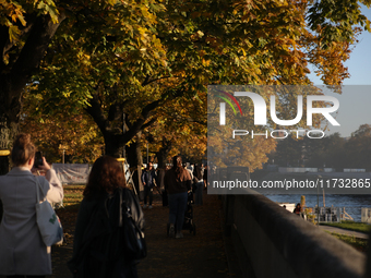 People walk among trees with autumn yellow leaves in Krakow, Poland, on October 19, 2024. (