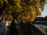 People walk among trees with autumn yellow leaves in Krakow, Poland, on October 19, 2024. (