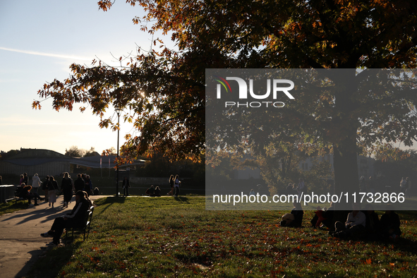 People walk among trees with autumn yellow leaves in Krakow, Poland, on October 19, 2024. 