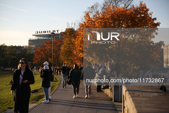 People walk among trees with autumn yellow leaves in Krakow, Poland, on October 19, 2024. 