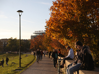 People walk among trees with autumn yellow leaves in Krakow, Poland, on October 19, 2024. (