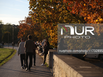 People walk among trees with autumn yellow leaves in Krakow, Poland, on October 19, 2024. (