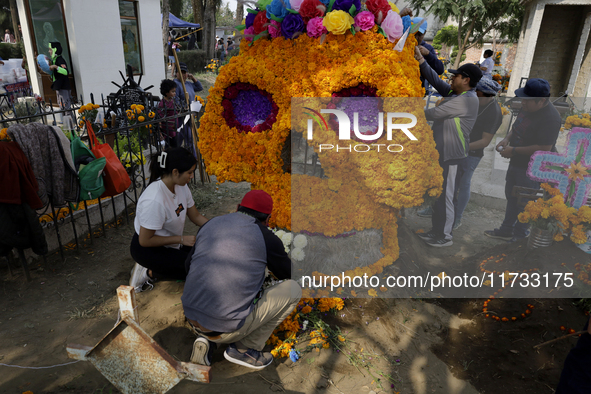 People attend the Tecomitl community pantheon in Mexico City, Mexico, on November 2, 2024, and decorate the graves of their deceased loved o...