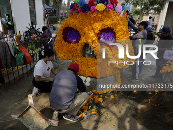 People attend the Tecomitl community pantheon in Mexico City, Mexico, on November 2, 2024, and decorate the graves of their deceased loved o...