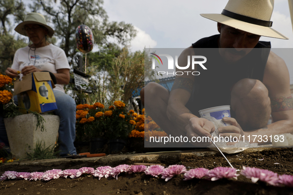 People attend the Tecomitl community pantheon in Mexico City, Mexico, on November 2, 2024, and decorate the graves of their deceased loved o...