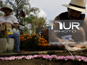 People attend the Tecomitl community pantheon in Mexico City, Mexico, on November 2, 2024, and decorate the graves of their deceased loved o...