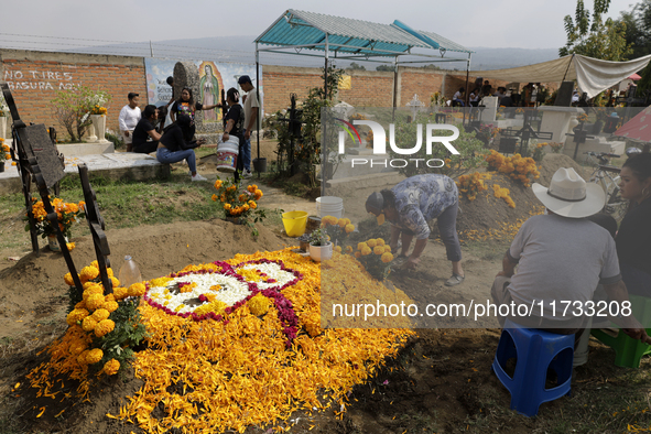 People attend the Tecomitl community pantheon in Mexico City, Mexico, on November 2, 2024, and decorate the graves of their deceased loved o...