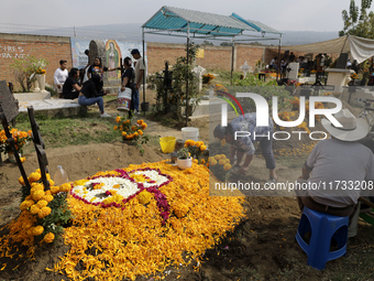 People attend the Tecomitl community pantheon in Mexico City, Mexico, on November 2, 2024, and decorate the graves of their deceased loved o...