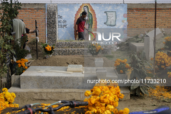 People attend the Tecomitl community pantheon in Mexico City, Mexico, on November 2, 2024, and decorate the graves of their deceased loved o...