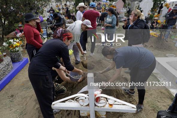 People attend the Tecomitl community pantheon in Mexico City, Mexico, on November 2, 2024, and decorate the graves of their deceased loved o...