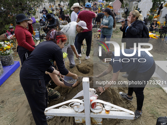 People attend the Tecomitl community pantheon in Mexico City, Mexico, on November 2, 2024, and decorate the graves of their deceased loved o...