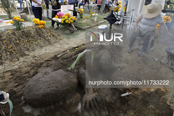 People attend the Tecomitl community pantheon in Mexico City, Mexico, on November 2, 2024, and decorate the graves of their deceased loved o...