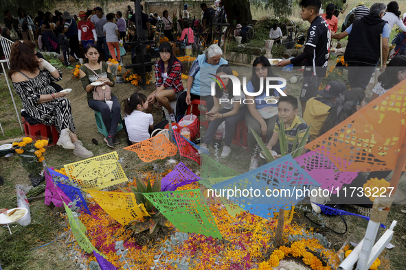 People attend the Tecomitl community pantheon in Mexico City, Mexico, on November 2, 2024, and decorate the graves of their deceased loved o...