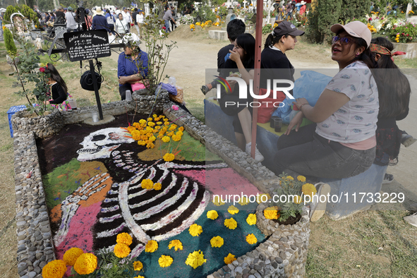 People attend the Tecomitl community pantheon in Mexico City, Mexico, on November 2, 2024, and decorate the graves of their deceased loved o...