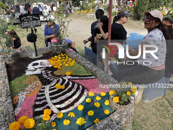 People attend the Tecomitl community pantheon in Mexico City, Mexico, on November 2, 2024, and decorate the graves of their deceased loved o...