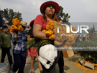 People attend the Tecomitl community pantheon in Mexico City, Mexico, on November 2, 2024, and decorate the graves of their deceased loved o...