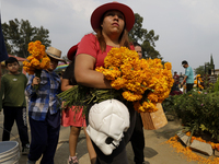 People attend the Tecomitl community pantheon in Mexico City, Mexico, on November 2, 2024, and decorate the graves of their deceased loved o...