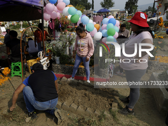 People attend the Tecomitl community pantheon in Mexico City, Mexico, on November 2, 2024, and decorate the graves of their deceased loved o...