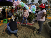 People attend the Tecomitl community pantheon in Mexico City, Mexico, on November 2, 2024, and decorate the graves of their deceased loved o...