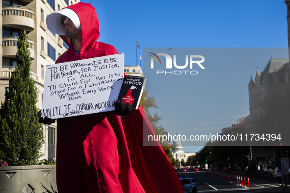 A person holds a sign and a book during the National Women's March at Freedom Plaza in Washington DC, USA, on November 2, 2024. Just days be...