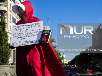 A person holds a sign and a book during the National Women's March at Freedom Plaza in Washington DC, USA, on November 2, 2024. Just days be...