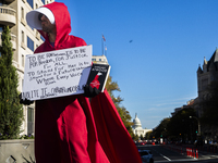 A person holds a sign and a book during the National Women's March at Freedom Plaza in Washington DC, USA, on November 2, 2024. Just days be...