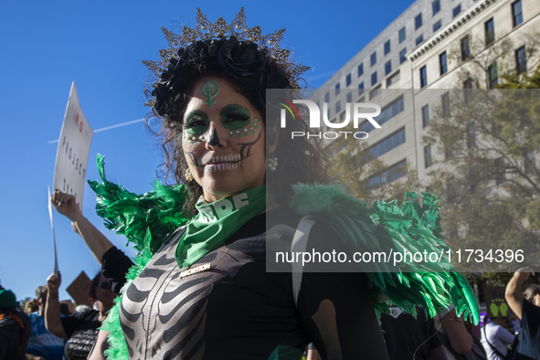 A person poses for photographs during the National Women's March at Freedom Plaza in Washington DC, USA, on November 2, 2024. Just days befo...