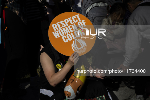 A person holds a sign during the National Women's March at Freedom Plaza in Washington DC, USA, on November 2, 2024. Just days before the US...