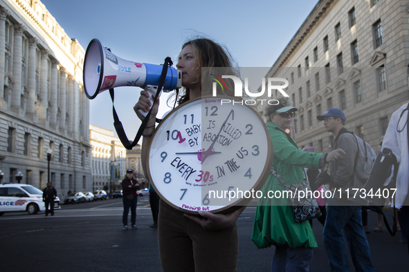 An anti-abortion rights activist holds a watch with some text during the National Women's March in Washington DC, USA, on November 2, 2024....