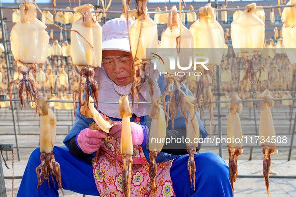 A worker dries squid at a seafood processing company in Zhanmao Industrial Park in Zhoushan, China, on November 3, 2024. 