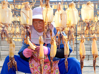 A worker dries squid at a seafood processing company in Zhanmao Industrial Park in Zhoushan, China, on November 3, 2024. (