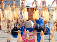 A worker dries squid at a seafood processing company in Zhanmao Industrial Park in Zhoushan, China, on November 3, 2024. (