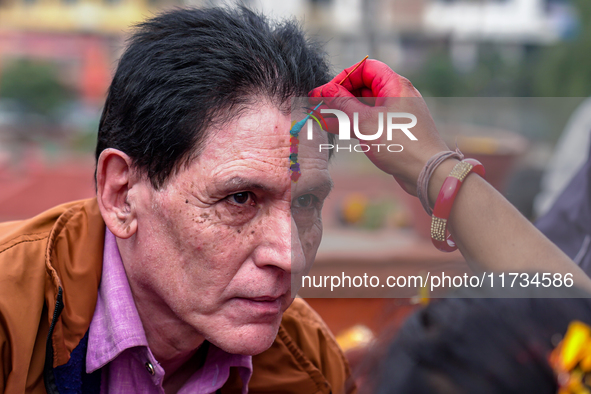 A sister applies tika on her brother's forehead, symbolizing protection and blessings, on the occasion of Bhaitika in Kathmandu, Nepal, on N...