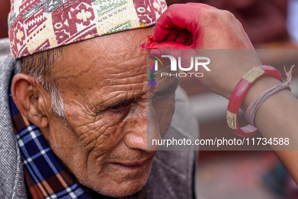 A sister applies tika on her brother's forehead, symbolizing protection and blessings, on the occasion of Bhaitika in Kathmandu, Nepal, on N...