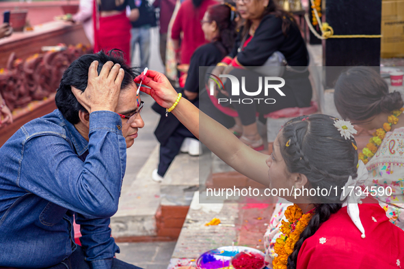 A sister applies tika on her brother's forehead, symbolizing protection and blessings, on the occasion of Bhaitika at Balgopaleshwar Temple...