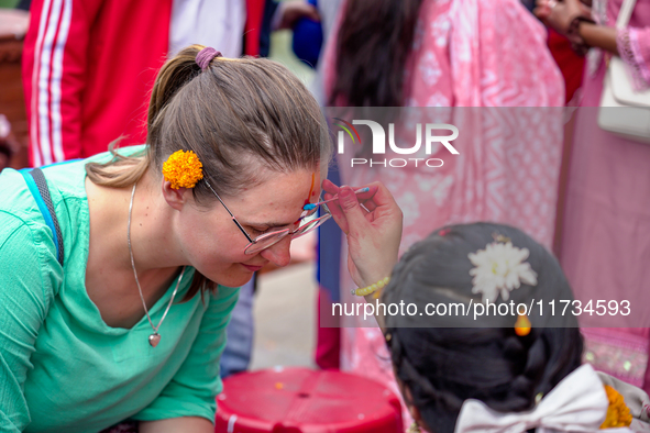 A sister applies tika on a tourist's forehead, symbolizing protection and blessings, on the occasion of Bhaitika at Balgopaleshwar Temple in...