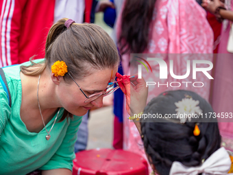 A sister applies tika on a tourist's forehead, symbolizing protection and blessings, on the occasion of Bhaitika at Balgopaleshwar Temple in...