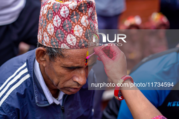 A sister applies tika on her brother's forehead, symbolizing protection and blessings, on the occasion of Bhaitika in Kathmandu, Nepal, on N...