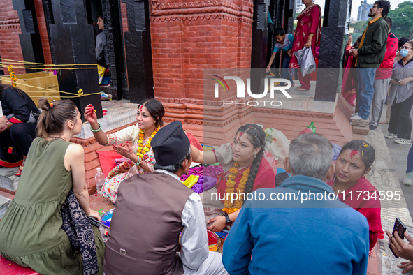 A sister applies tika on her brother's forehead, symbolizing protection and blessings, on the occasion of Bhaitika in Kathmandu, Nepal, on N...