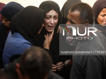 Mourners weep near the bodies of Palestinians killed in an Israeli airstrike amid the conflict between Israel and Hamas in Deir al-Balah, ce...