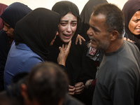 Mourners weep near the bodies of Palestinians killed in an Israeli airstrike amid the conflict between Israel and Hamas in Deir al-Balah, ce...