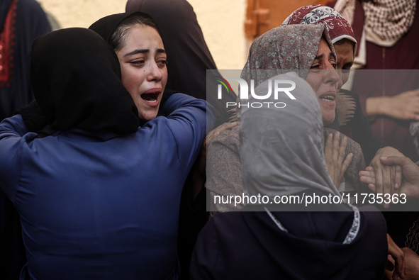 Mourners weep near the bodies of Palestinians killed in an Israeli airstrike amid the conflict between Israel and Hamas in Deir al-Balah, ce...